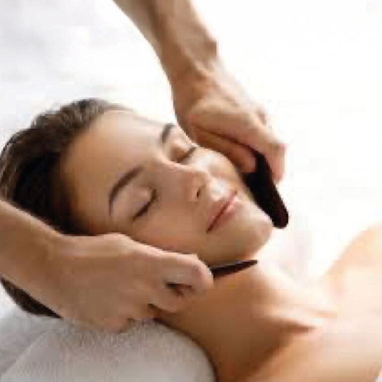 A woman receiving a Gua Sha facial.