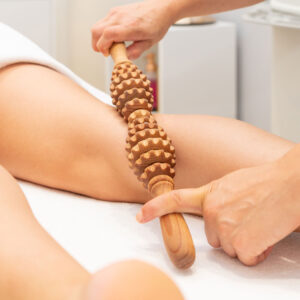 Wood therapy massage on someones leg using a wooden tool.