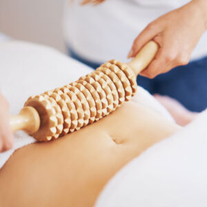 A wood therapy tool being pressed onto someones stomach.